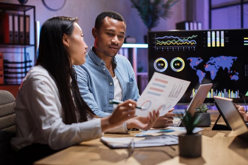 Un homme et une femme examinant des graphiques de performance dans un bureau, représentant l’utilisation de Notion AI pour une organisation optimisée