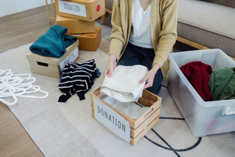Femme organisant des vêtements dans une boîte de dons pour le nettoyage de printemps.