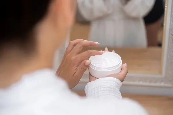 Gros plan d’une main appliquant une crème hydratante pour le visage