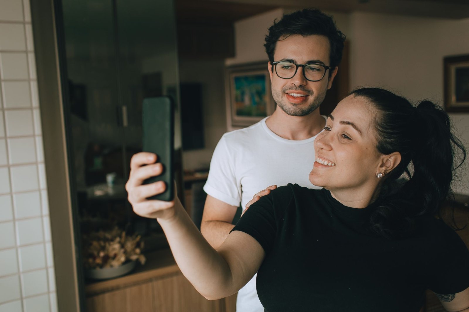 Couple souriant prenant un selfie à l'intérieur