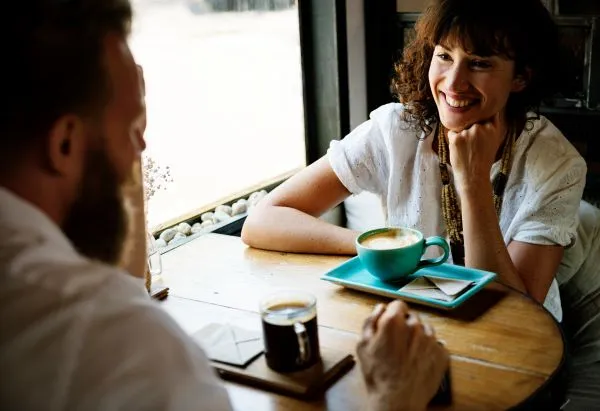 2 adultes discutant joyeusement dans un café, représentant la convivialité et les rencontres sociales