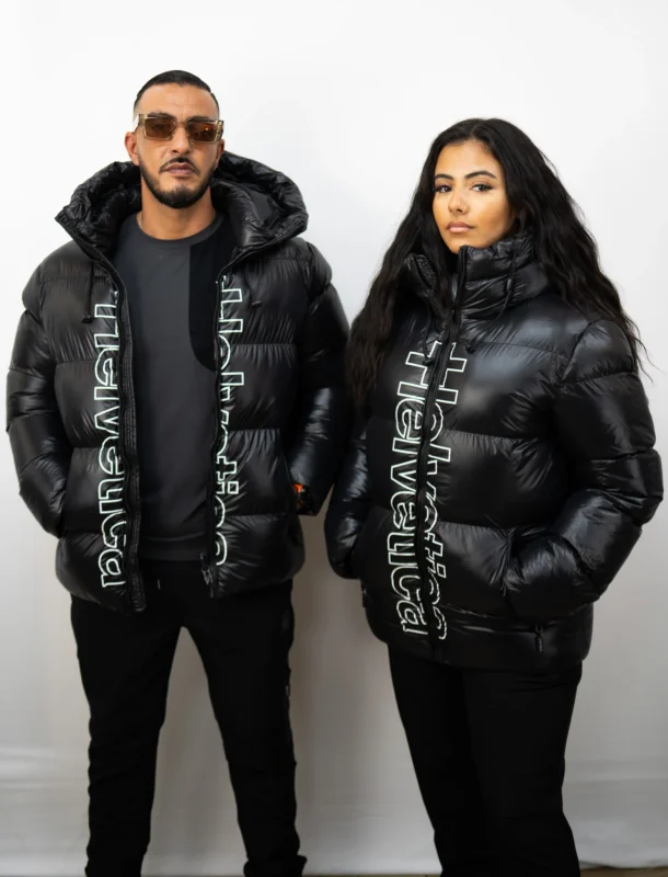 Un homme et une femme portent la doudoune Helvetica Silver noire avec logo vertical Helvetica