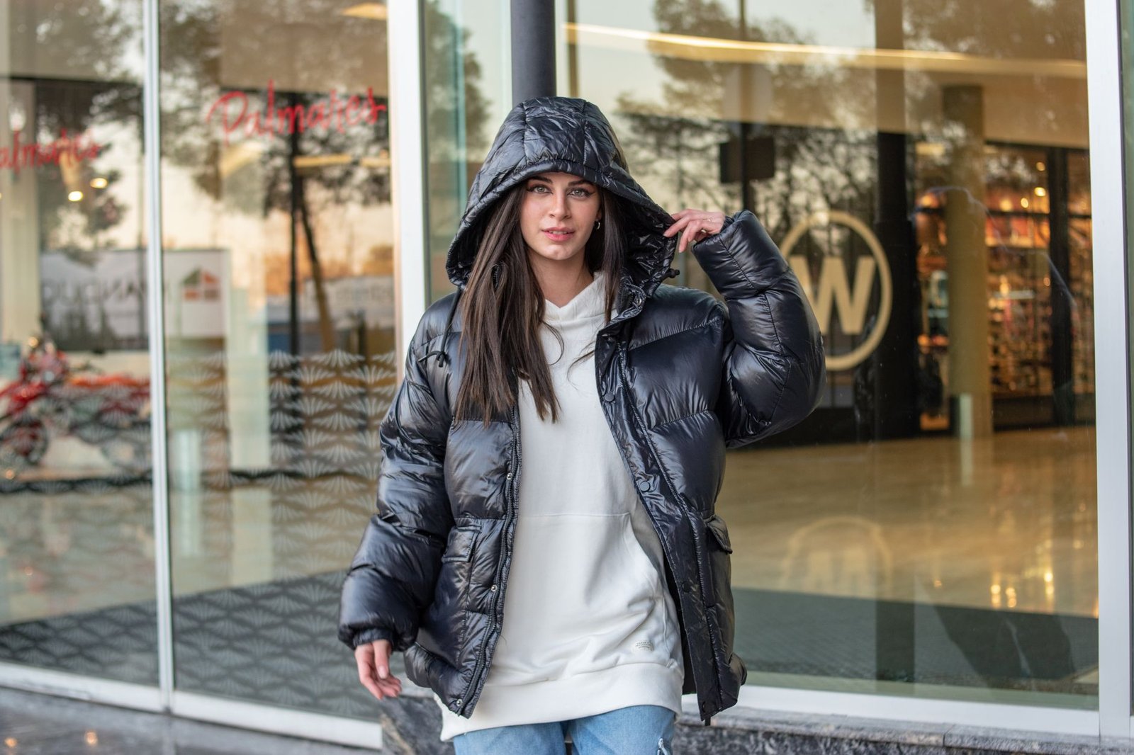 Femme portant une doudoune noire devant un fond urbain