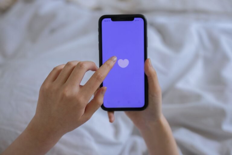 Mains tenant un smartphone avec une icône de cœur à l'écran