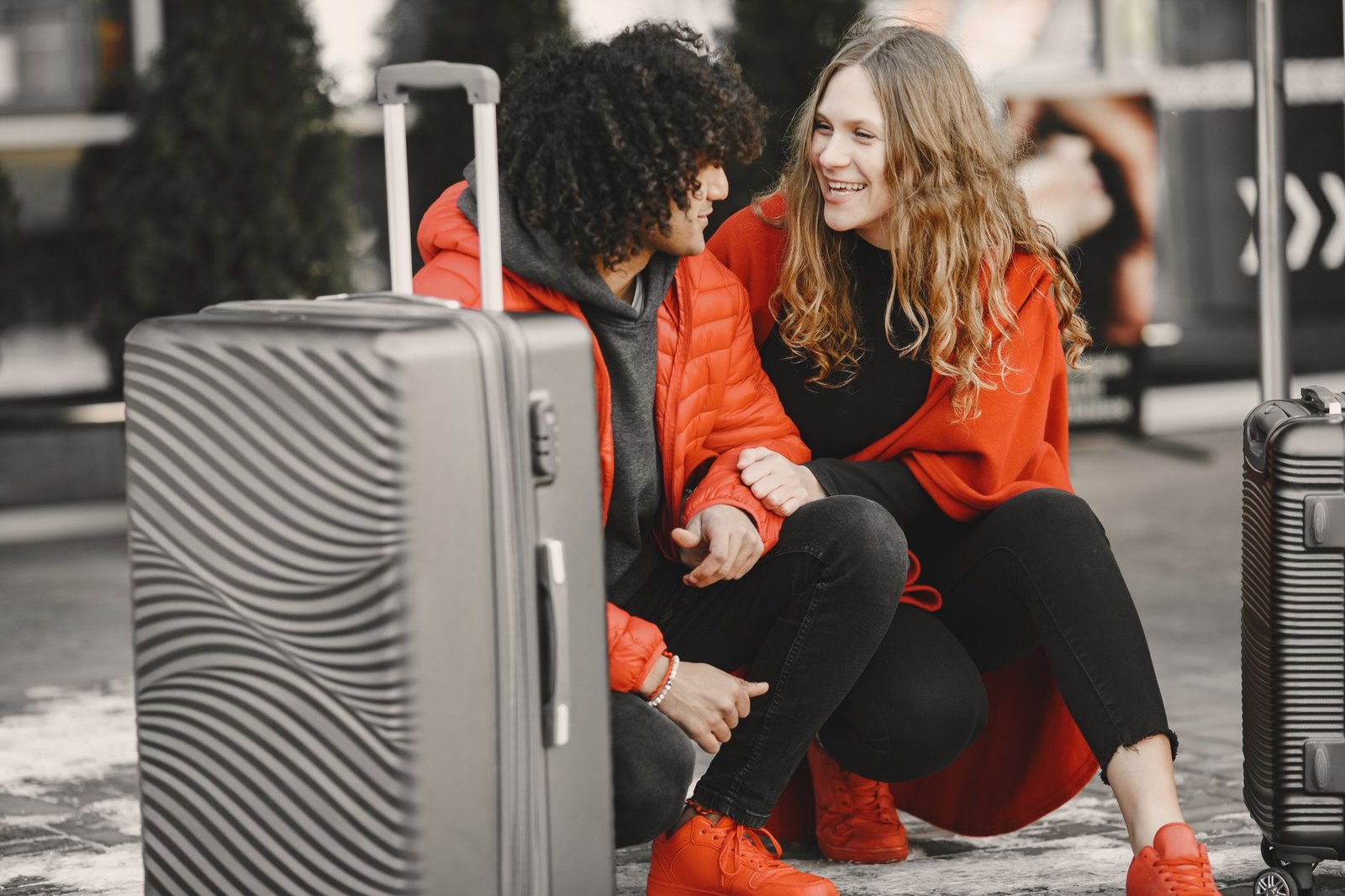 Couple souriant assis avec leurs bagages, prêts à partir en week-end