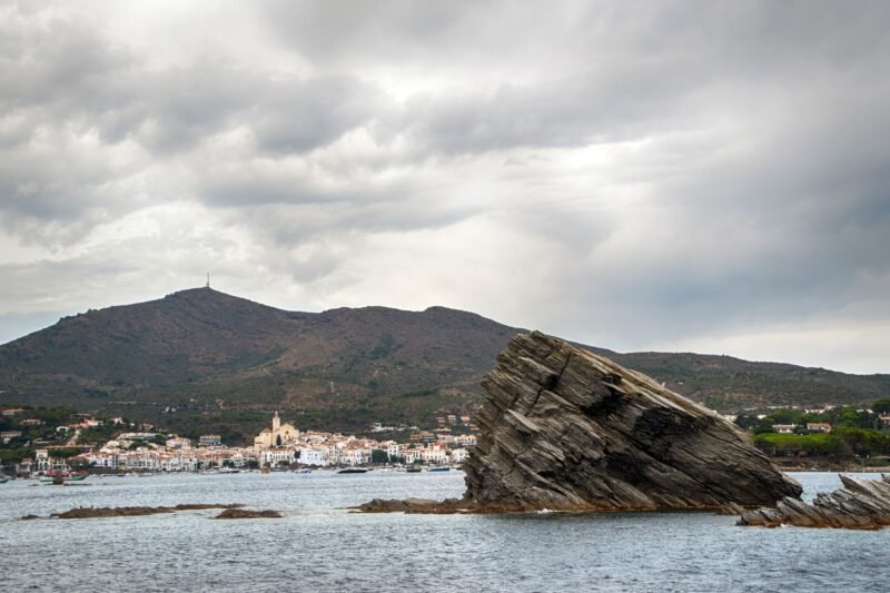 Rocher en bord de mer près de Cadaqués, avec le village au pied de la montagne
