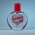 Flacon de parfum Lovemore Cherrylicious (eau de parfum) avec bouchon rose, sur fond bleu.