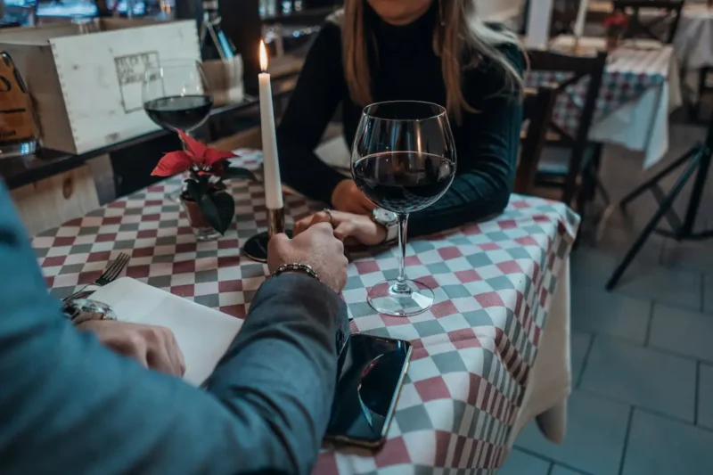Couple partageant un dîner romantique au restaurant avec des verres de vin rouge et une bougie allumée sur une table