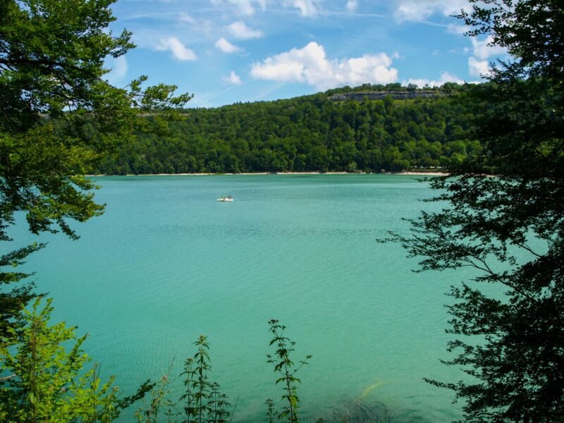 Lac aux eaux turquoise entouré de forêts dans le Jura