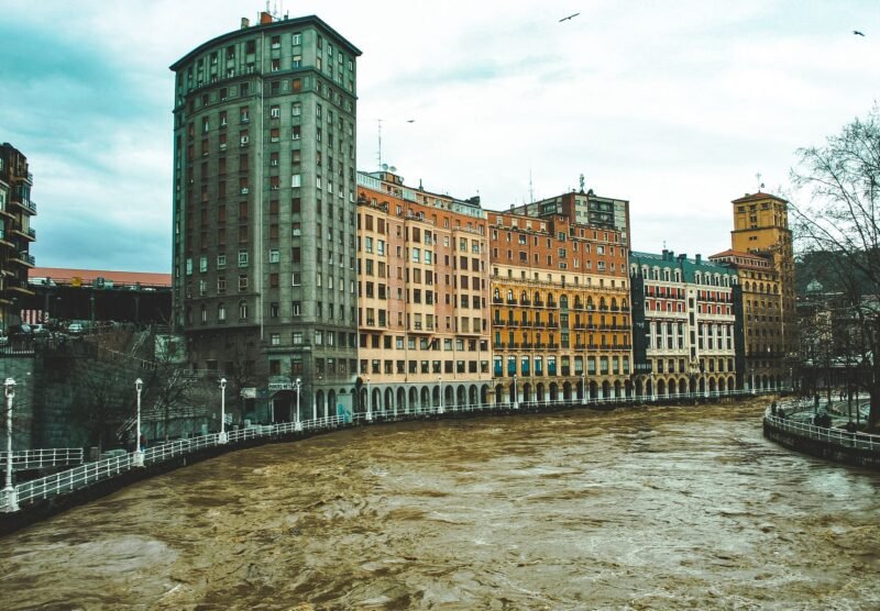 Façades colorées et arcades le long de la Nervión à Bilbao, sous un ciel gris