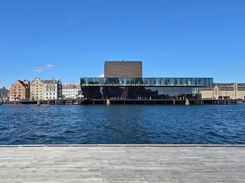 L'Opéra de Copenhague se reflétant dans l'eau du port sous un ciel bleu