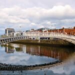 Le pont Ha'penny au-dessus de la Liffey à Dublin, reflété dans l'eau sous un ciel nuageux
