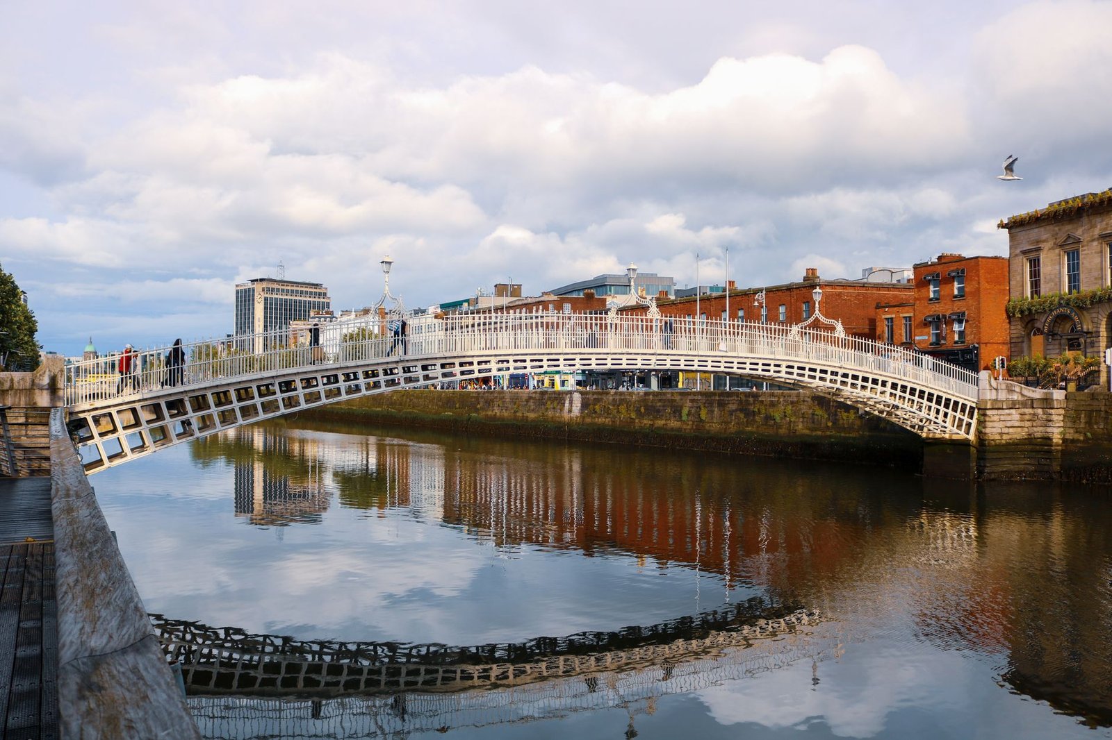 Le pont Ha'penny au-dessus de la Liffey à Dublin, reflété dans l'eau sous un ciel nuageux