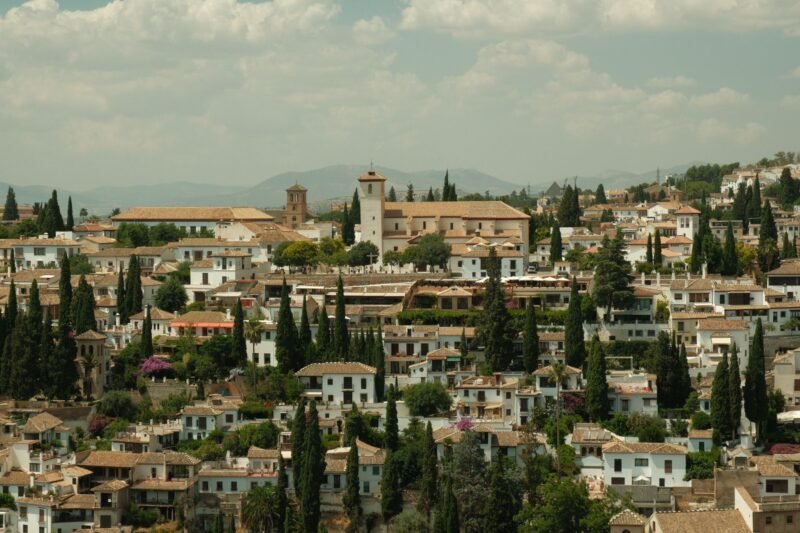 Les maisons blanches et les cyprès de l'Albaicín de Grenade, vus depuis les hauteurs, avec la montagne au loin