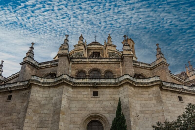 Le chevet de pierre de la cathédrale de Grenade, vu d'en bas sous un ciel bleu nuageux