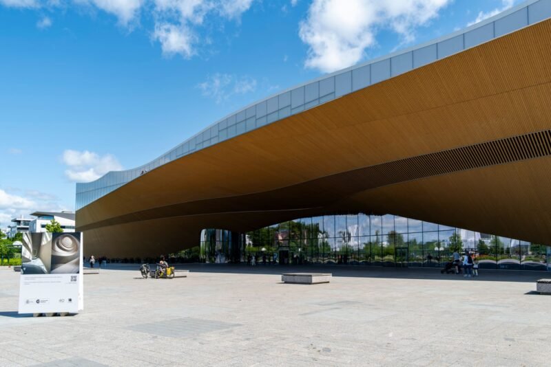 La façade de bois courbe et les baies vitrées de la bibliothèque Oodi à Helsinki, sous un ciel bleu