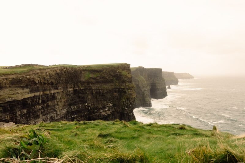 Les falaises de Moher plongeant dans l'océan Atlantique, avec la lande verte au premier plan, dans le comté de Clare