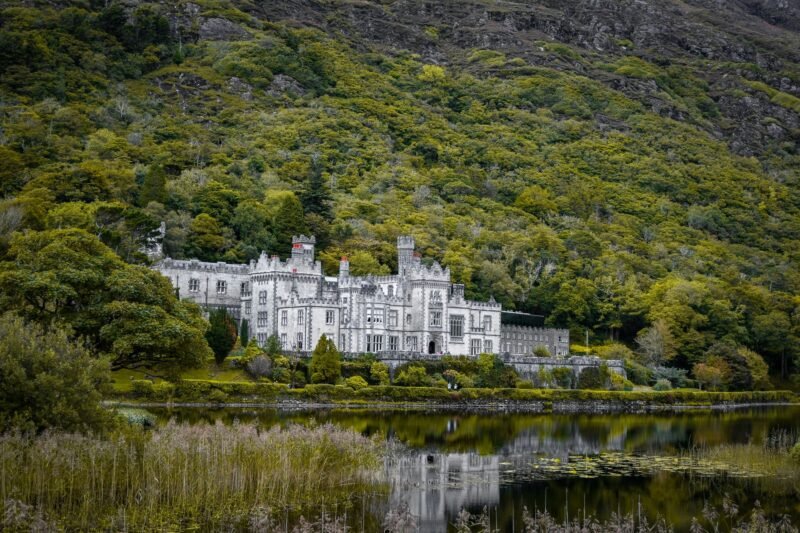 L'abbaye de Kylemore, de style néogothique, se reflétant dans un lac au pied d'une colline boisée, dans le Connemara