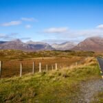 Une route qui traverse la lande du Connemara vers des montagnes, sous un ciel bleu, en Irlande
