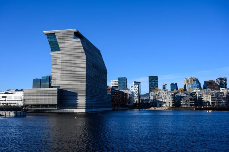 La tour du musée Munch et le front de mer de Bjørvika à Oslo, reflétés dans l'eau sous un ciel bleu