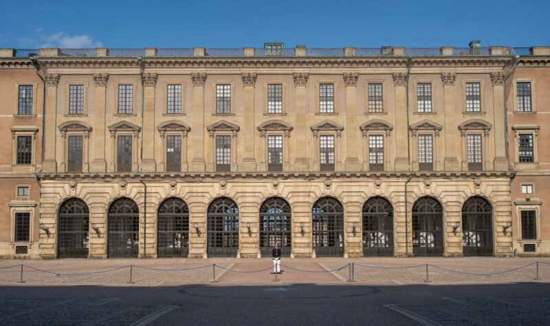 La façade baroque du Palais royal de Stockholm sous le soleil, avec un garde devant l'entrée