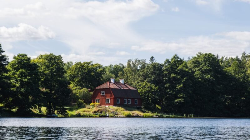 Une maison suédoise rouge au bord d'un lac, entourée de forêt, dans la région de Stockholm